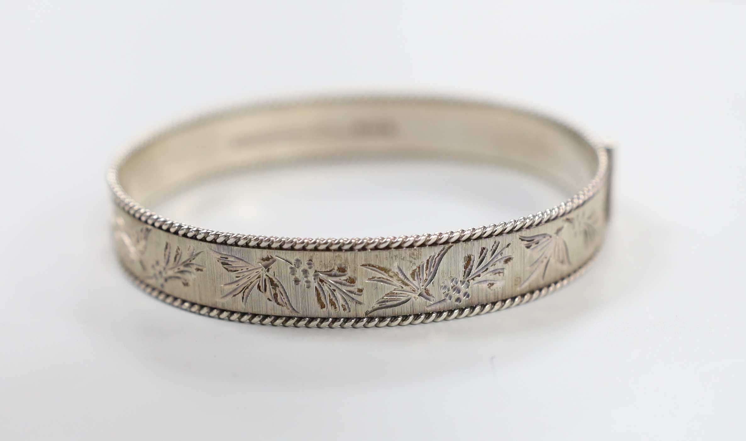 A silver hinged bangle and three other items including a paste set brooch.